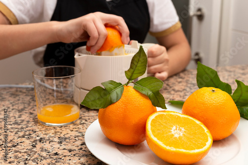 Girl holding a citrus juicer with orange and fresh citrus fruit in the kitchen.