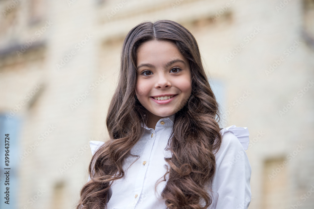 Fototapeta premium Happy beautiful kid with cute look wear long wavy hair outdoors, beauty
