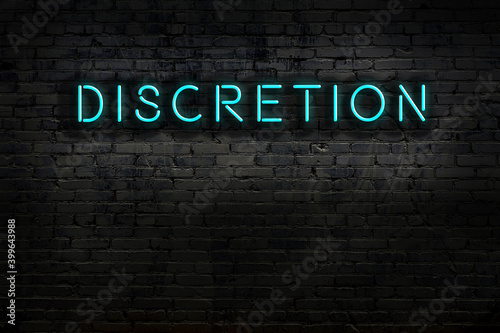 Night view of neon sign on brick wall with inscription discretion