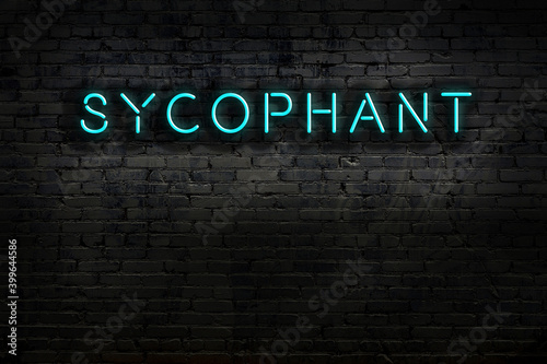 Neon sign. Word sycophant against brick wall. Night view photo