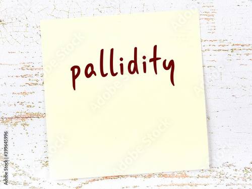 Yellow sticky note on wooden wall with handwritten word pallidity photo