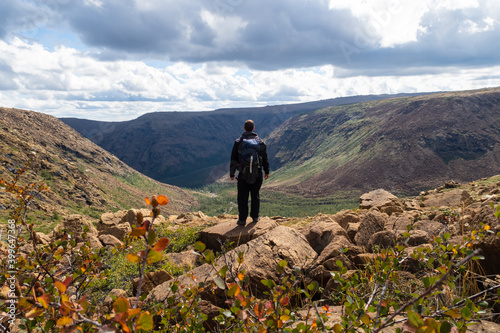Back view of a man carrying a backpack standing in the Gaspésie national park, Canada