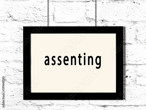 Photography Black frame hanging on white brick wall with inscription assenting
