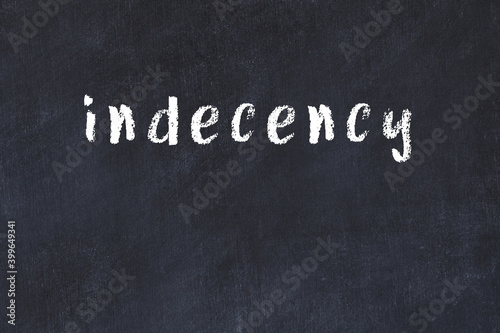 College chalk desk with the word indecency written on in photo