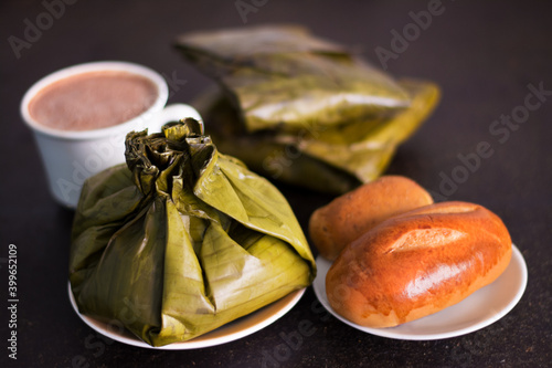 Primer plano de un delicioso tamal con chocolate y pan con unas hallacas de fondo photo