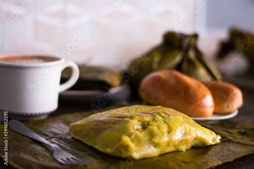 Primer plano de relleno de una hallaca junto a chocolate, pan y un tamal. Primer plano del interior de un tamal