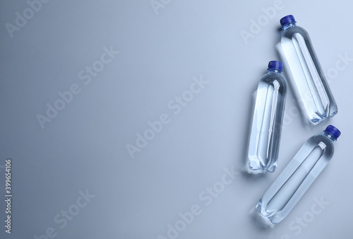 Plastic bottles with water on white background, flat lay. Space for text