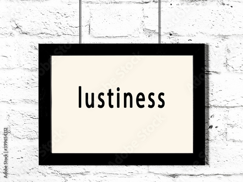 Black frame hanging on white brick wall with inscription lustiness