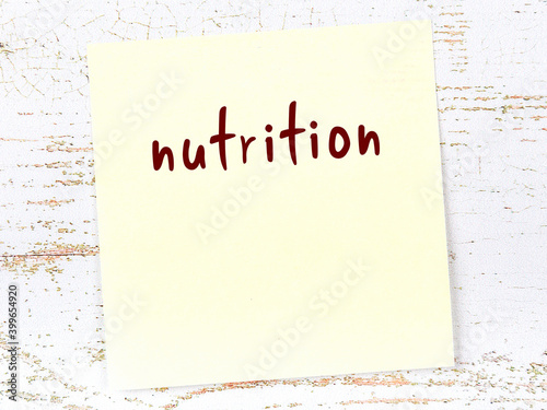 Foto Yellow sticky note on wooden wall with handwritten word nutrition
