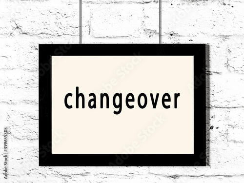 Black frame hanging on white brick wall with inscription changeover