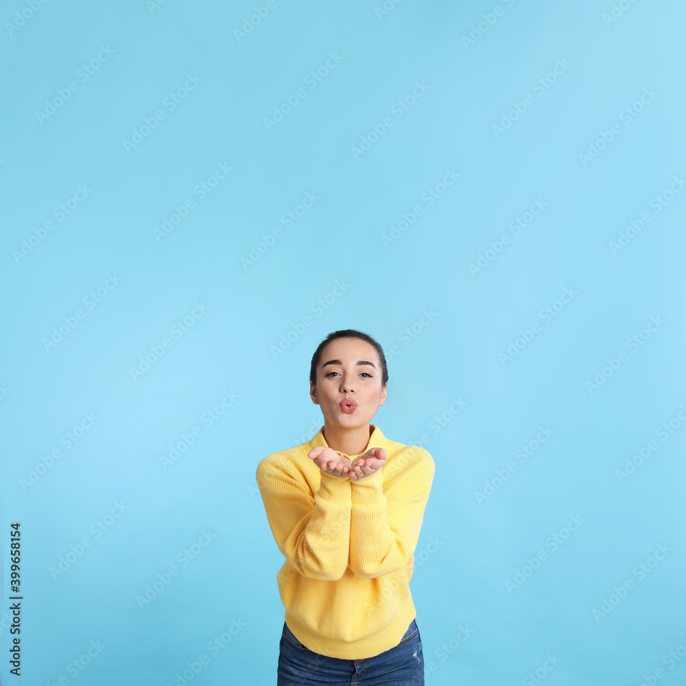 Beautiful young woman wearing yellow warm sweater on light blue background. Space for text Beautiful young woman wearing yellow warm sweater on light blue background. Space for text