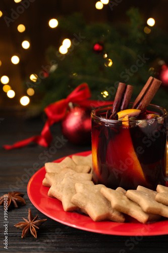 Aromatic mulled wine and cookies on wooden table, closeup