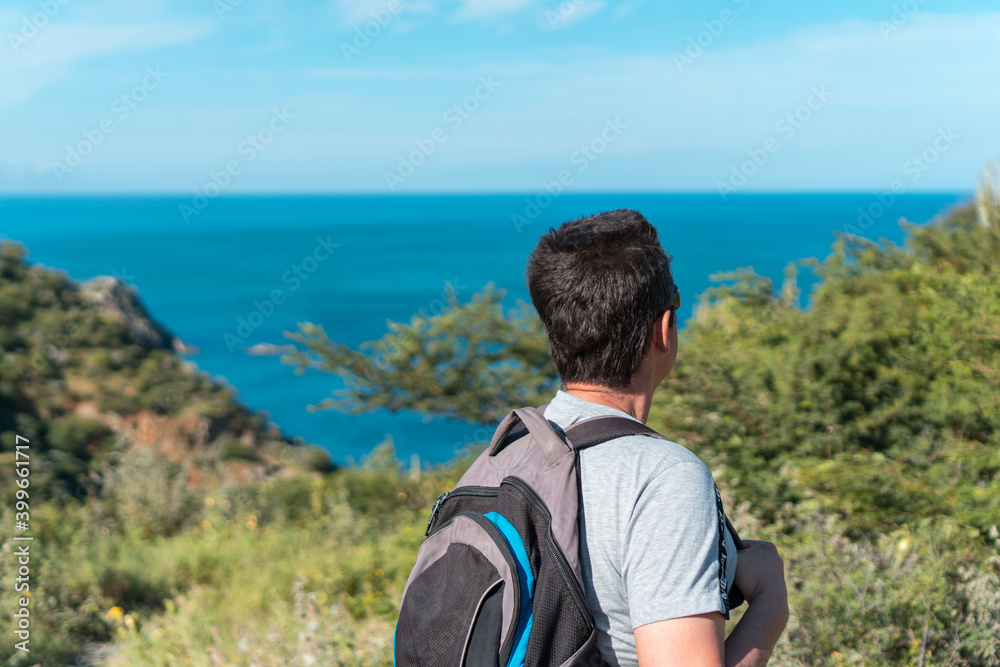 Man with backpacks walking on the mountain and enjoying the ocean view