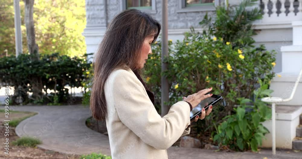 Attractive, well-dressed businesswoman in profile pose texting on cell phone outdoors. Successful and confident older asian model. Bokeh background of office building. Attractive, well-dressed businesswoman in profile pose texting on cell phone outdoors. Successful and confident older asian model. Bokeh background of office building.