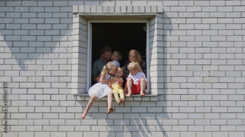 The concept of a large family. A friendly family hugs each other in the window of their house.