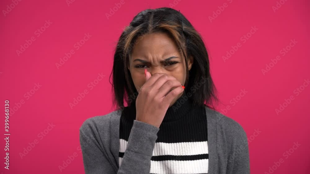 Lovely young African-American woman smells something stinky repulsive