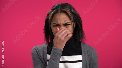 Lovely young African-American woman smells something stinky repulsive