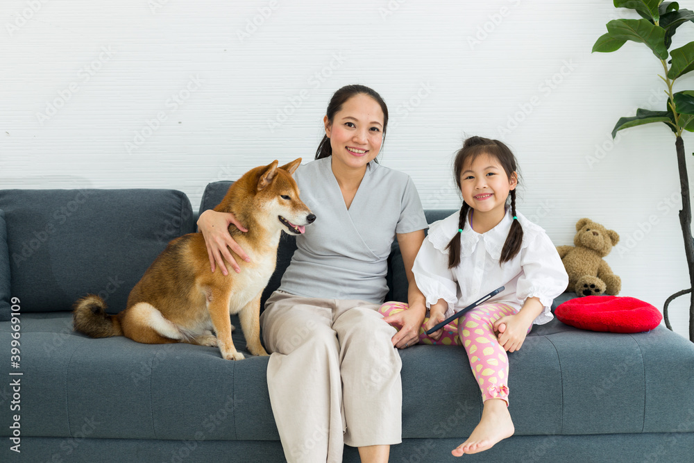 Lovely family, mother and daughter with their favorite dog sit on sofa.