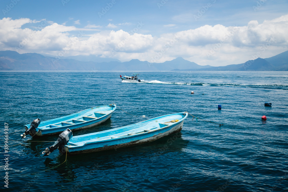 Two blue boats on lake Atitlan with view on volcanic mountians in Santa Cruz la Laguna, Guatemala