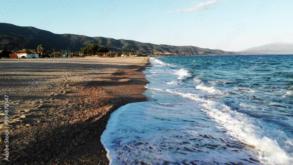 View of Aegean sea coast in Asprovalta at sunset from the drone. Sunbeds with umbrellas. Rough sea, waves with foam. Greece View of Aegean sea coast in Asprovalta at sunset from the drone. Sunbeds with umbrellas. Rough sea, waves with foam. Greece