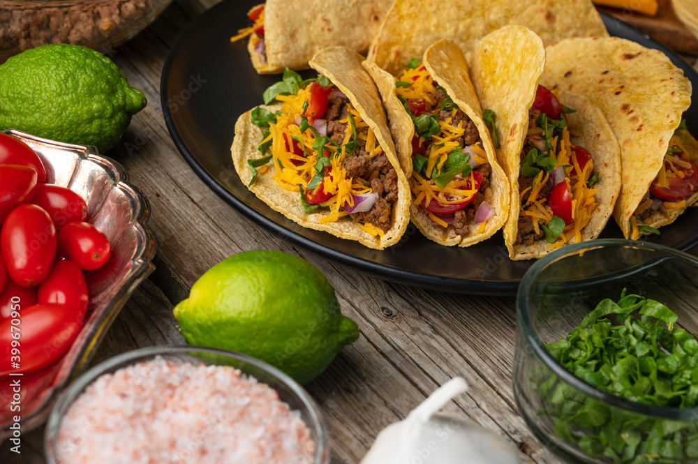 Close-up view of plate with hot mexican tacos on rustic wooden table with ingredients for cooking background. Concept of traditional meal. Appetizing photo for menu or cookbook. Close-up view of plate with hot mexican tacos on rustic wooden table with ingredients for cooking background. Concept of traditional meal. Appetizing photo for menu or cookbook.