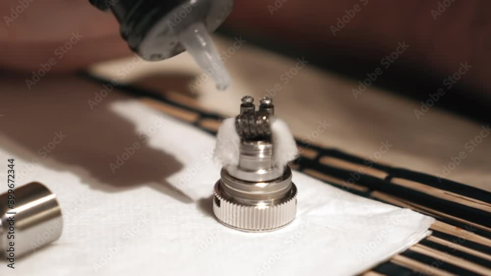 Man filling cotton for vaping with a transparent liquid Man filling cotton for vaping with a transparent liquid