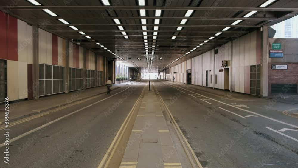Man cycling beneath an underpass on a deserted city street Man cycling beneath an underpass on a deserted city street