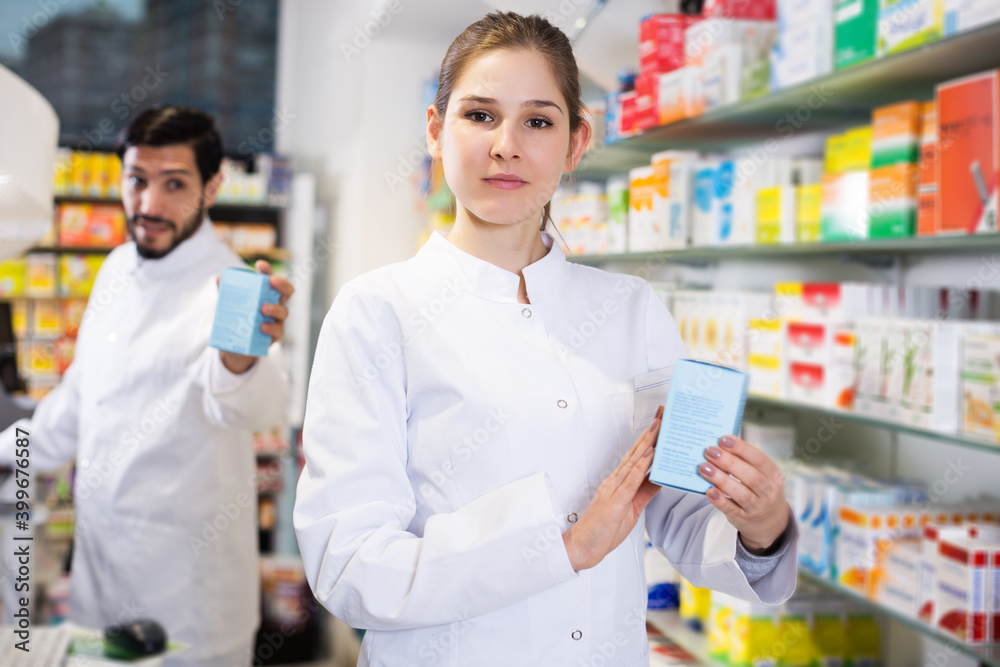 woman pharmacist who is standing with medicine on her work place in apothecary.