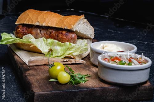 primer plano de choripan comida tipica y tradicional de argentina sandwich de pan con chorizo de cerdo con condimentos salsa criolla lechuga cebolla pimiento morron tomate mayonesa kechup y moztaza photo