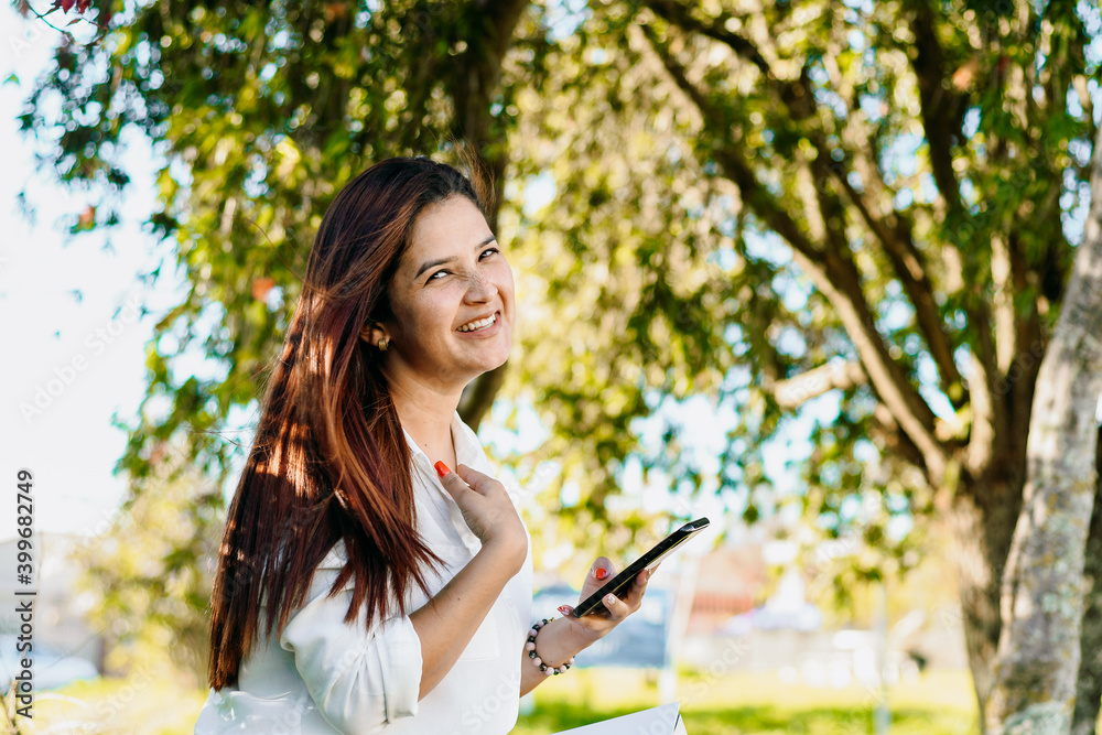 Naklejka premium Executive woman using her phone on a park bench.