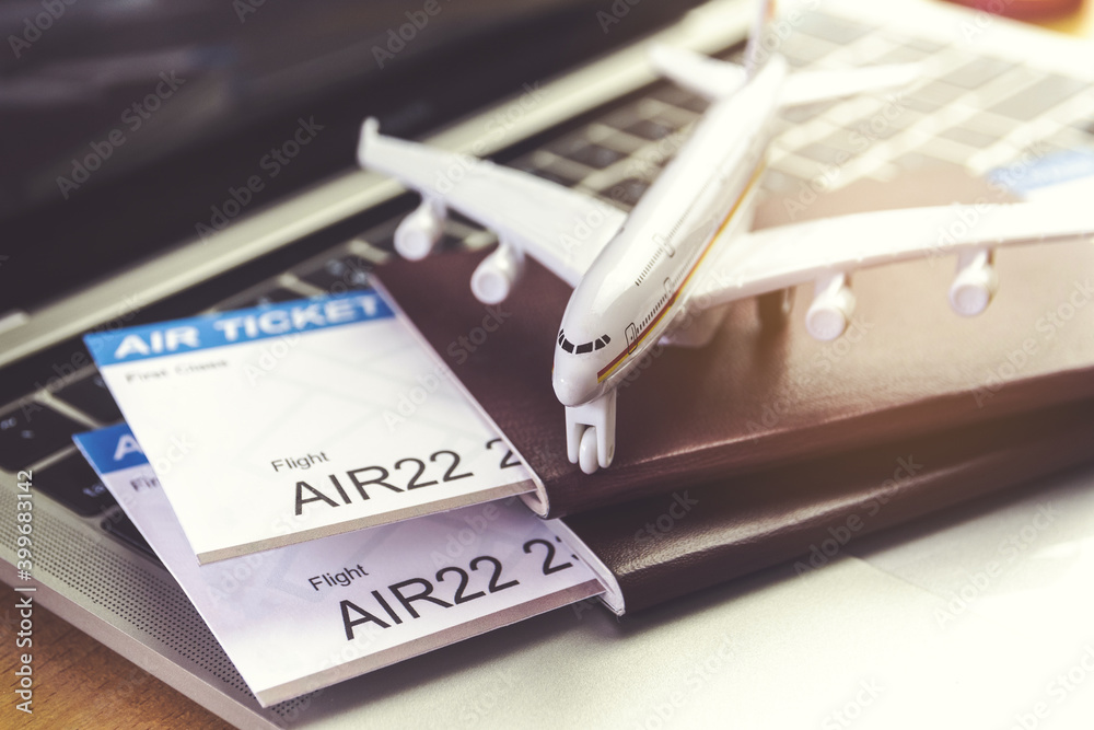 Air tickets and passports near laptop computer and airplane on table. Online ticket booking concept Air tickets and passports near laptop computer and airplane on table. Online ticket booking concept