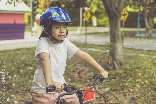 Asian girl learns to ride bike in park. Portrait of a cute kid on bicycle.