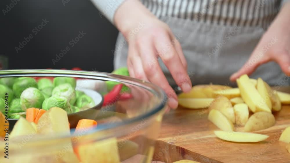 Placing chopped potatoes into a transparent glass bowl in 4k. Concept of adding a pile of sliced fresh potatoes into a bowl in slow motion.