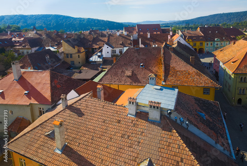 View from clock tower of Sighisoara tile roofs in sunny autumn day, Romania photo