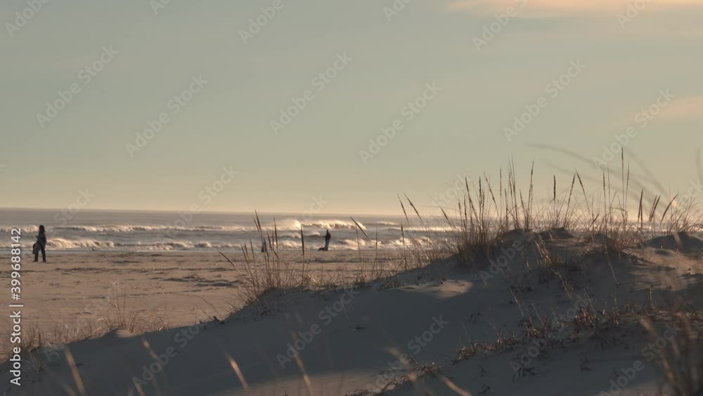 People At The Coast With Waves Rolling On A Sunset - Atlantic Ocean In New Jersey - wide shot People At The Coast With Waves Rolling On A Sunset - Atlantic Ocean In New Jersey - wide shot
