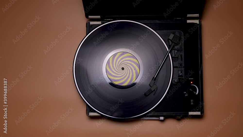 The man shifts the needle on the vinyl record. Top view of male hands and vintage turntable on brown table background. Retro concept. Slow motion. Close up.