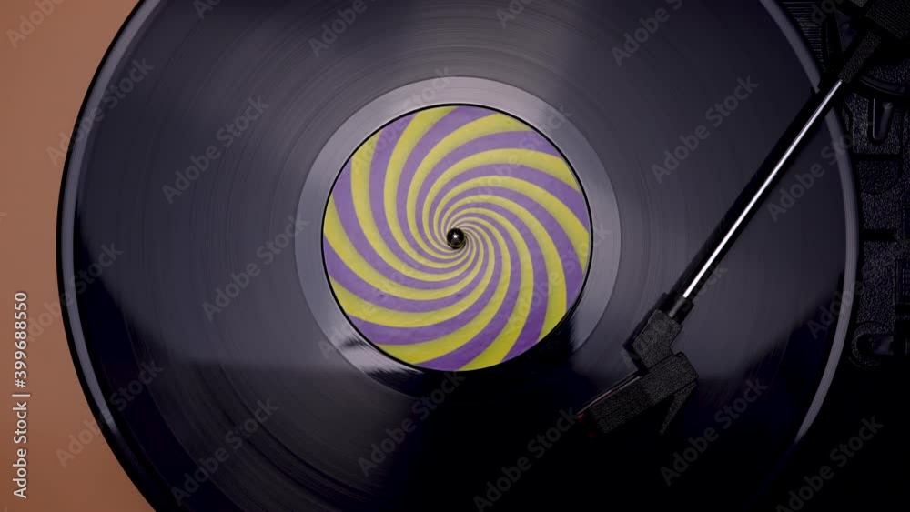 Vintage turntable with rotating black vinyl record, stylus and needle on brown background. Top view of an old music player. Retro concept. Close up. Slow motion.