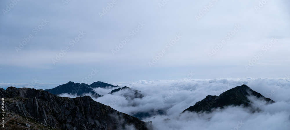 Panoramic view of Kiso Mountains Range engulfed in thick clouds in early autumn at Senjojiki Cirque in Nagano Prefecture, Japan.