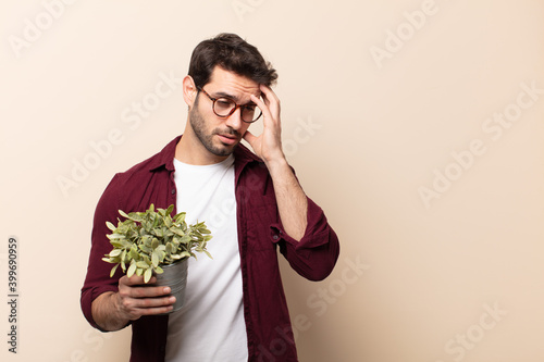 young handsome man feeling bored, frustrated and sleepy after a tiresome, dull and tedious task, holding face with hand