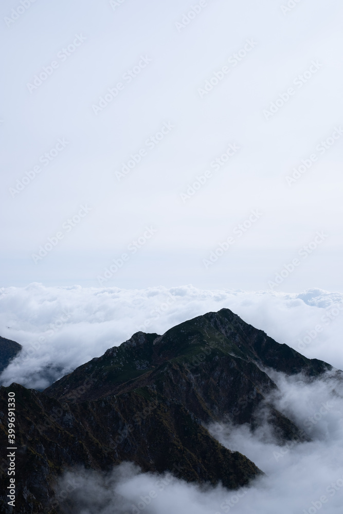View of Kiso Mountains Range engulfed in thick clouds in early autumn at Senjojiki Cirque in Nagano Prefecture, Japan.