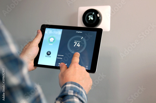 Man is Adjusting a temperature using a tablet with smart home app in modern living room