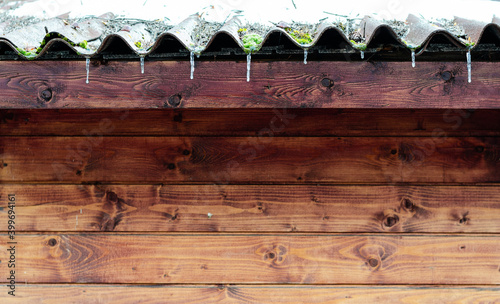 Ice spikes hanging from the edge of the roof in winter