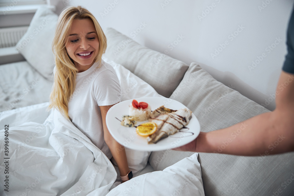 Positive delighted female person having breakfast in bed Positive delighted female person having breakfast in bed