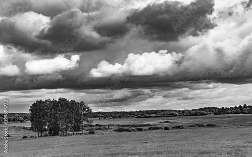 Summer black and white landscape with clouds over the fields.
