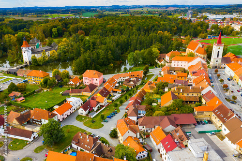 Aerial view of historical centre of Blatna in autumn day overlooking gothic church bell tower and ancient Water castle, South Bohemian Region, Czech Republic.. photo