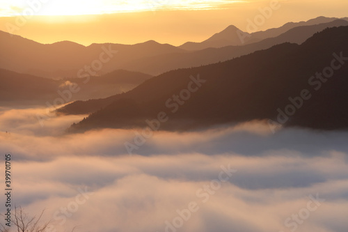 朝日に照らされる雲海と山脈のシルエット