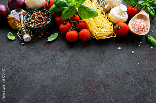 Healthy mediterranean diet, ingredients for Italian meal, spaghetti, tomatoes, basil, olive oil, garlic, peppers on black background