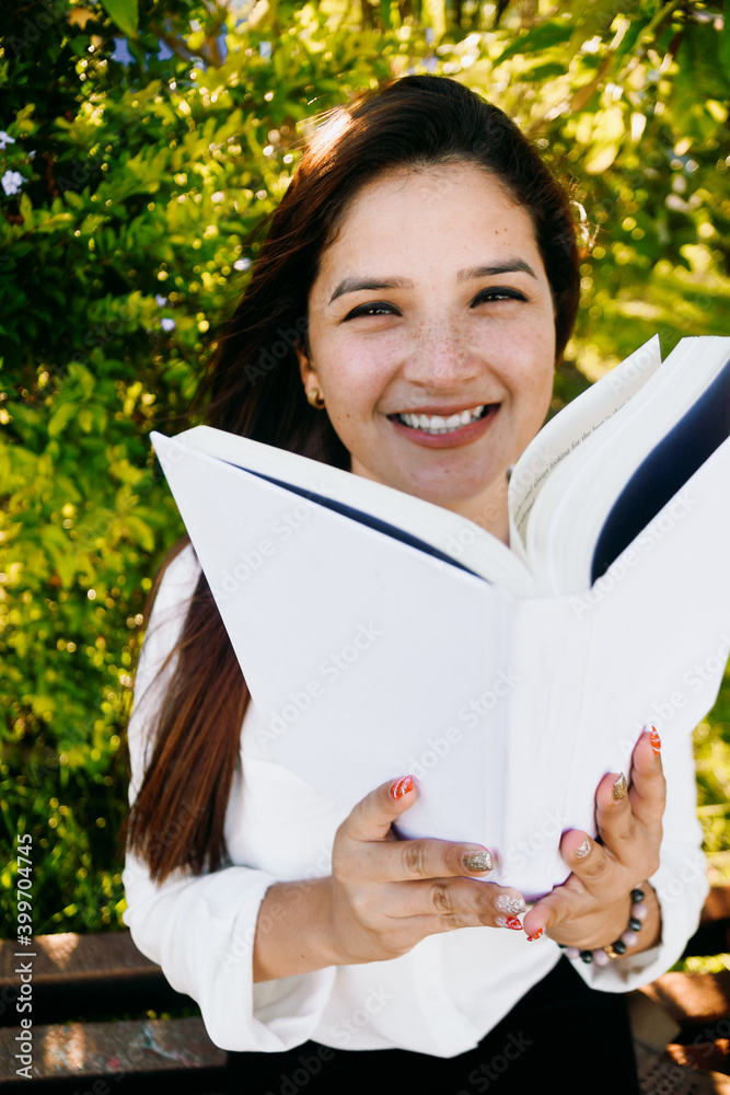 Fototapeta premium Woman with cute freckles smiling and hiding her face with a book