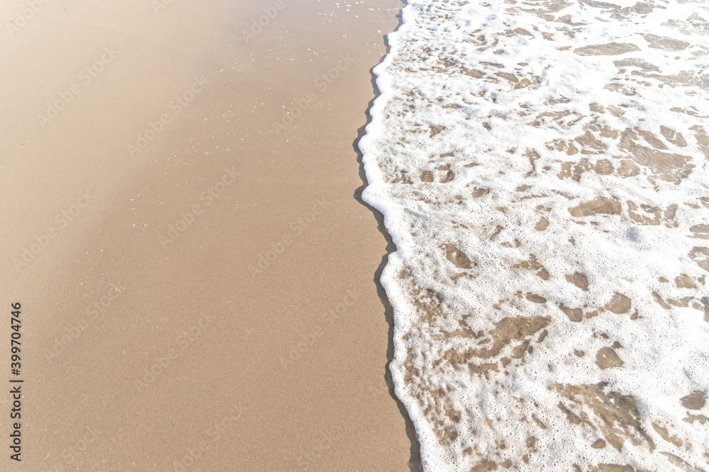 Sparkling waves hitting the shore on the beach, sand beige background image.