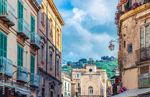 Typical italian narrow street of Tropea town historical centre with old buildings with balconies and shutter windows, Vibo Valentia, Calabria, Southern Italy